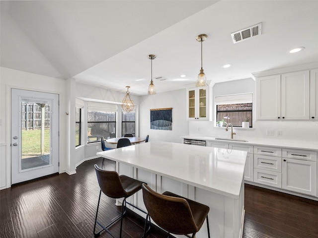 kitchen featuring light countertops, a kitchen bar, a sink, and visible vents