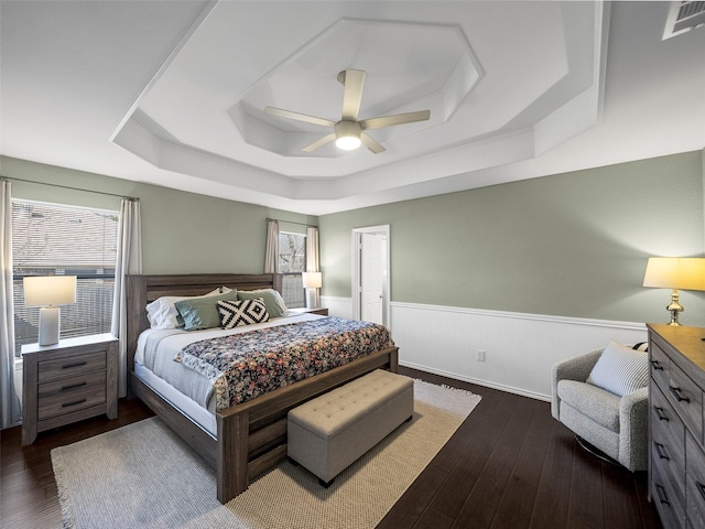 bedroom with a wainscoted wall, multiple windows, a raised ceiling, and visible vents