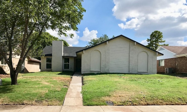 view of front of property with central AC unit, a front yard, and brick siding