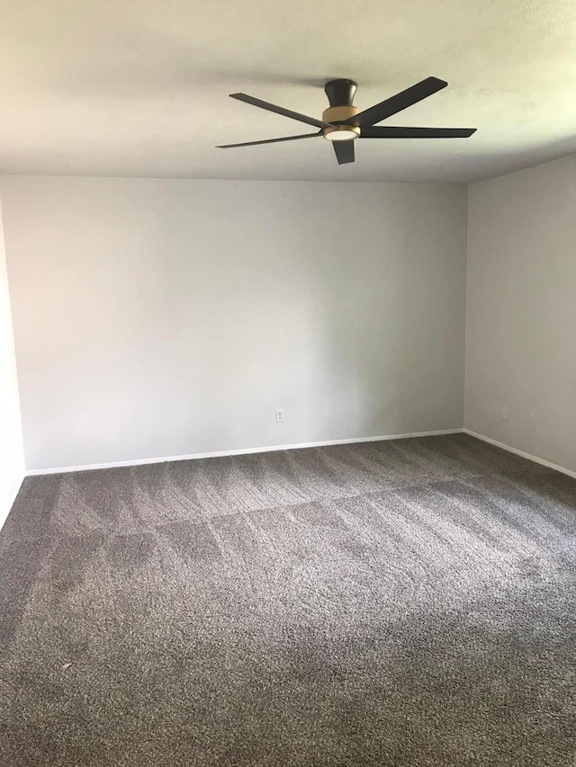 empty room with carpet floors, a ceiling fan, and baseboards