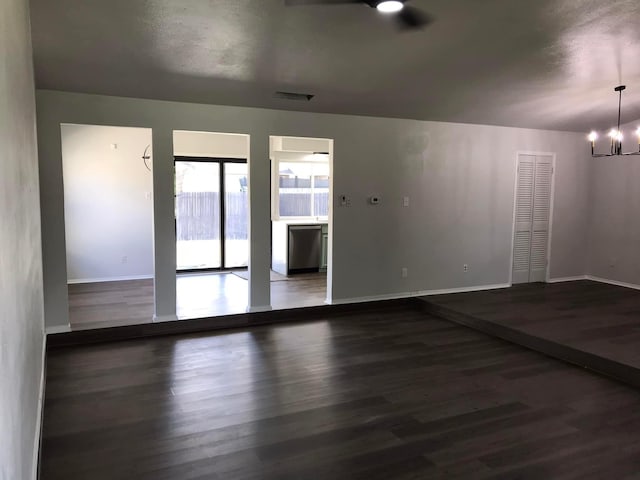 unfurnished room with visible vents, a notable chandelier, baseboards, and wood finished floors