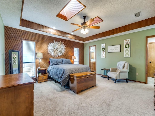 carpeted bedroom with a skylight, visible vents, wooden walls, a textured ceiling, and baseboards