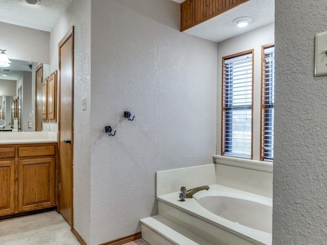 bathroom with a textured wall, a textured ceiling, vanity, and a bath