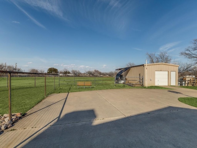 view of patio featuring a rural view, a detached garage, fence, and an outdoor structure