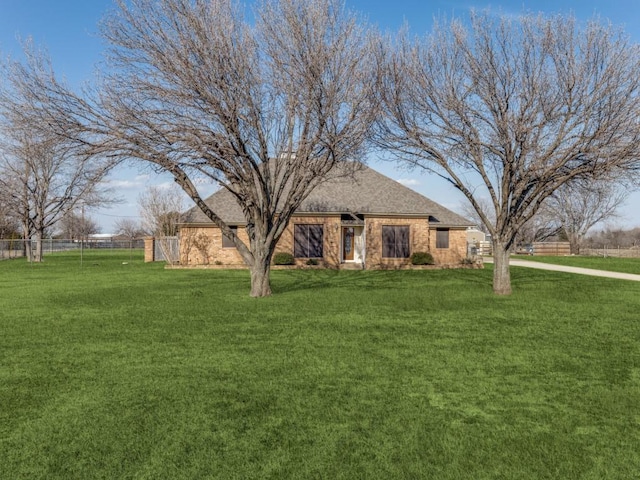 view of front of home with a shingled roof, brick siding, fence, and a front lawn