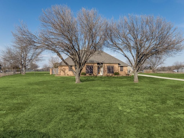 view of front facade featuring brick siding, fence, and a front yard