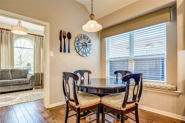 dining area with dark wood-style flooring, vaulted ceiling, and baseboards