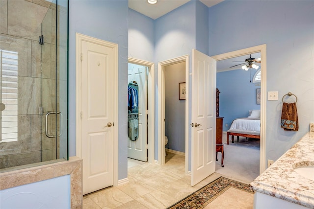 ensuite bathroom with a closet, toilet, a stall shower, vanity, and baseboards