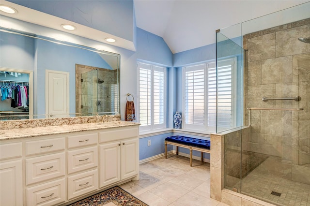 full bathroom with baseboards, tile patterned flooring, vaulted ceiling, vanity, and a shower stall