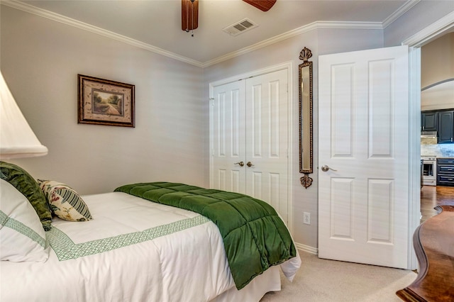 bedroom with a closet, visible vents, ornamental molding, a ceiling fan, and light carpet