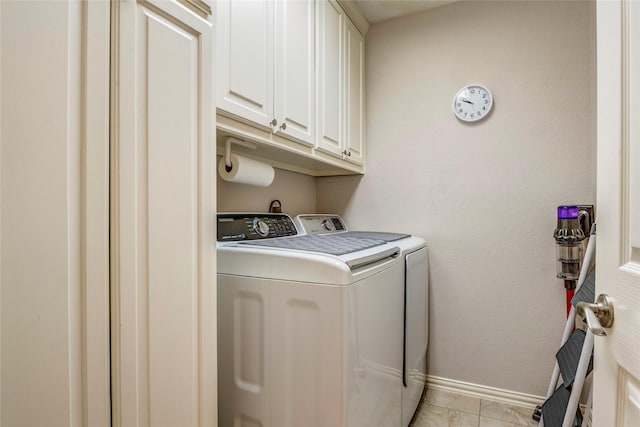 clothes washing area featuring light tile patterned floors, washer and clothes dryer, cabinet space, and baseboards