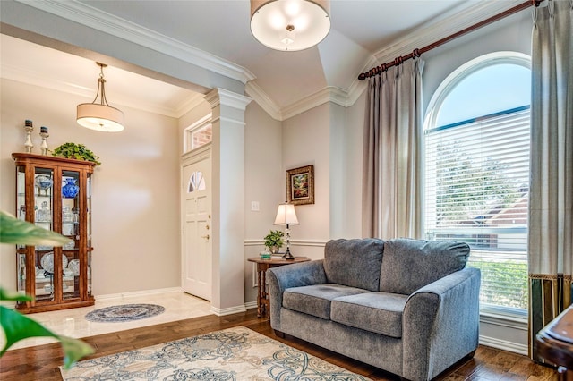 living area featuring decorative columns, baseboards, crown molding, and wood finished floors