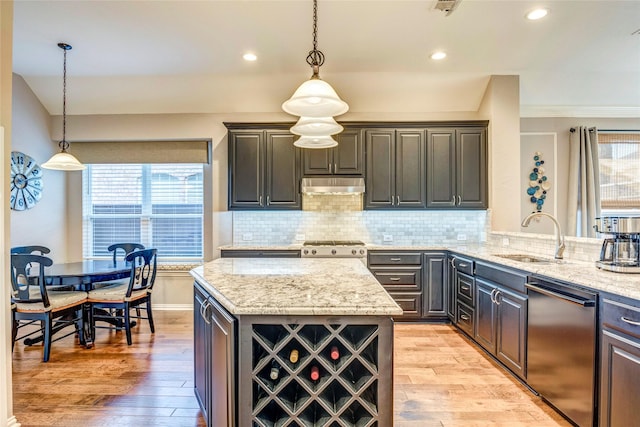 kitchen featuring decorative backsplash, dishwasher, under cabinet range hood, stainless steel range with gas cooktop, and a sink