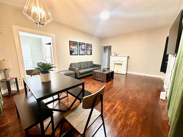 dining space featuring a chandelier, dark wood-type flooring, a fireplace, and baseboards