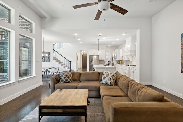 living area with a healthy amount of sunlight, dark wood-style floors, baseboards, and arched walkways