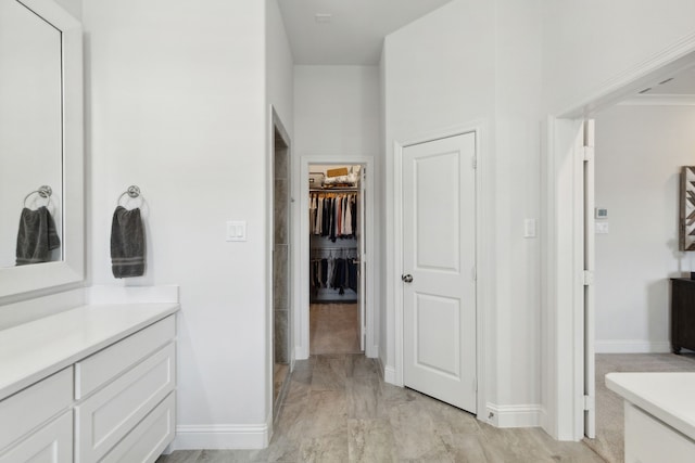 bathroom featuring vanity, baseboards, and a spacious closet