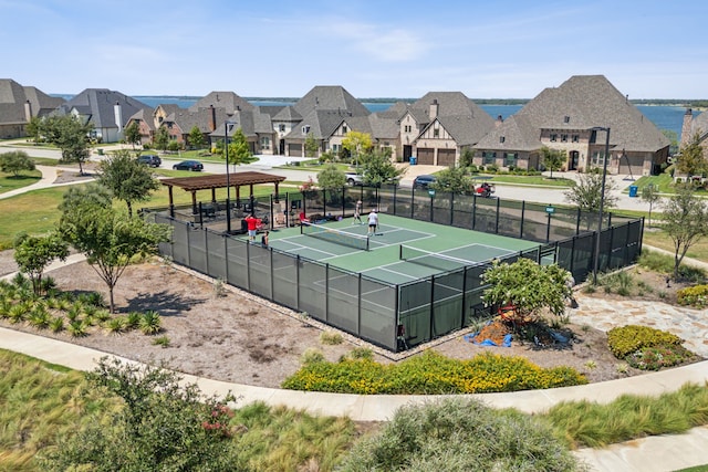 view of tennis court with a residential view and fence