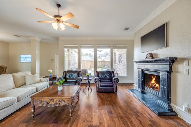 living room featuring a fireplace, decorative columns, visible vents, ornamental molding, and wood finished floors