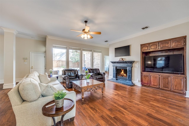 living area featuring crown molding, visible vents, dark wood finished floors, and a lit fireplace