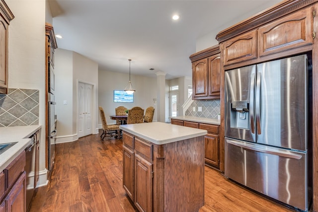 kitchen with light countertops, a center island, stainless steel fridge, and dark wood-style flooring