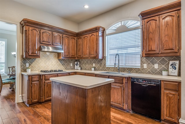 kitchen with black dishwasher, dark wood finished floors, stainless steel gas stovetop, a sink, and under cabinet range hood