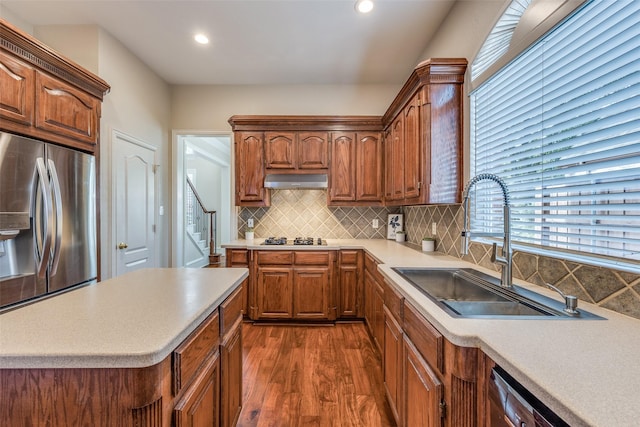 kitchen featuring range hood, dark wood finished floors, stainless steel appliances, light countertops, and a sink