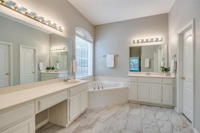 full bath with a garden tub, marble finish floor, two vanities, and a sink