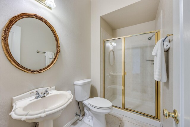 bathroom with a sink, a shower stall, toilet, and tile patterned flooring