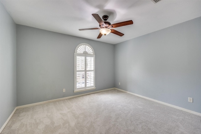 carpeted spare room featuring ceiling fan and baseboards