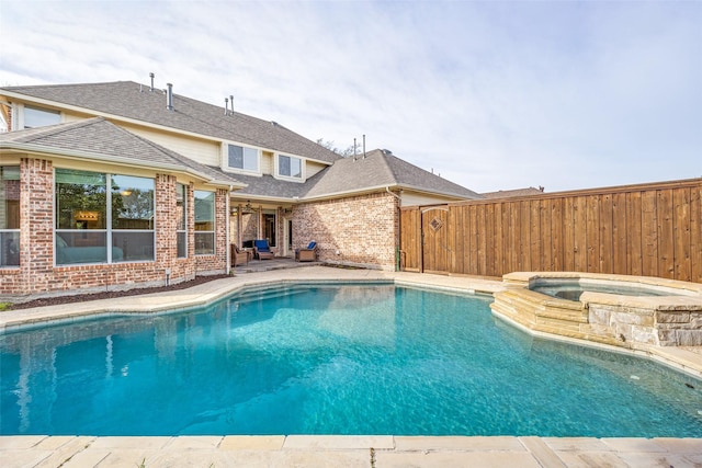 view of pool with a pool with connected hot tub, a patio area, and fence