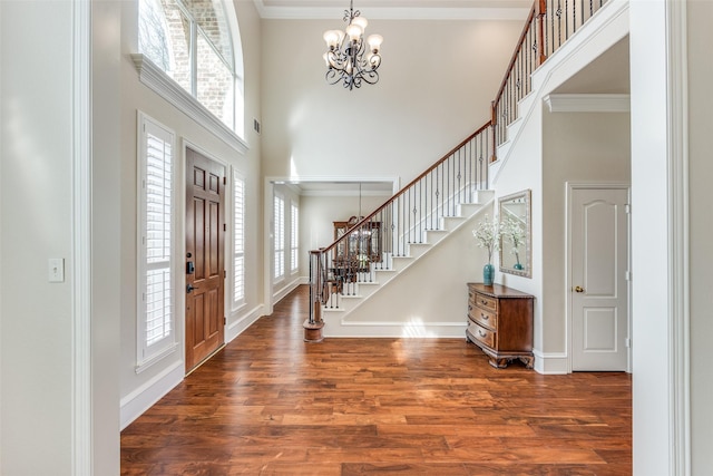 foyer with stairs, crown molding, a high ceiling, and wood finished floors