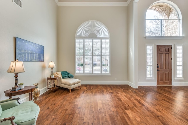 entrance foyer with baseboards, visible vents, wood finished floors, and ornamental molding