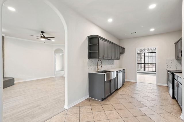 kitchen featuring open shelves, tasteful backsplash, light countertops, a sink, and black / electric stove