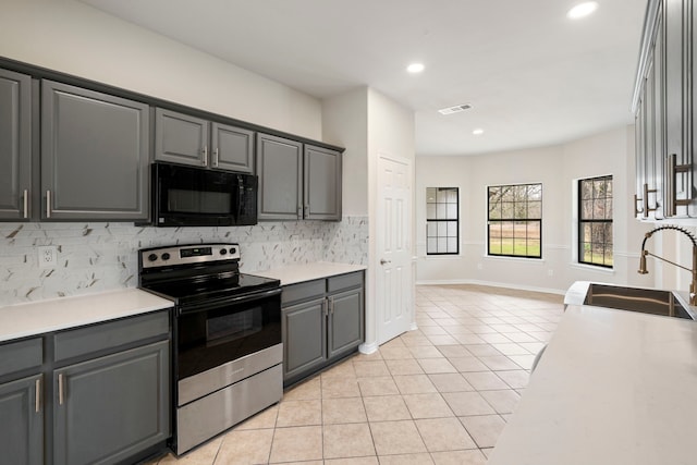 kitchen featuring black microwave, light tile patterned floors, gray cabinetry, electric range, and a sink