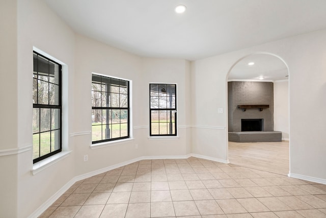 spare room with light tile patterned floors, a brick fireplace, baseboards, and recessed lighting