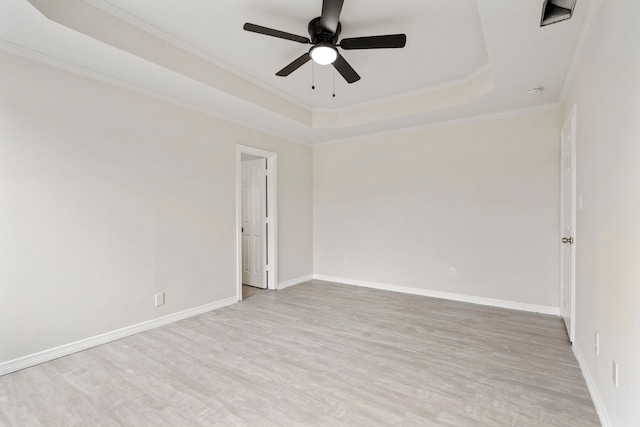 unfurnished room featuring ornamental molding, a raised ceiling, baseboards, and wood finished floors