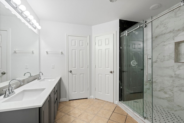 full bathroom featuring double vanity, a marble finish shower, a sink, and tile patterned floors