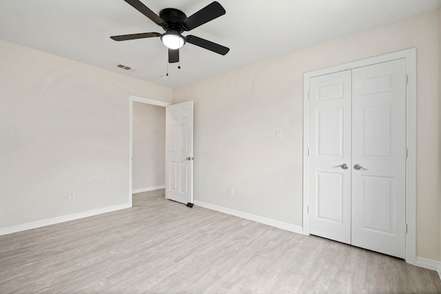 unfurnished bedroom featuring baseboards, visible vents, ceiling fan, wood finished floors, and a closet