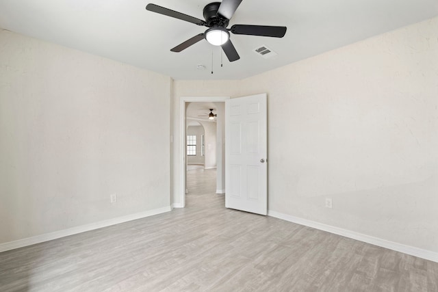 empty room featuring baseboards, ceiling fan, visible vents, and light wood-style floors