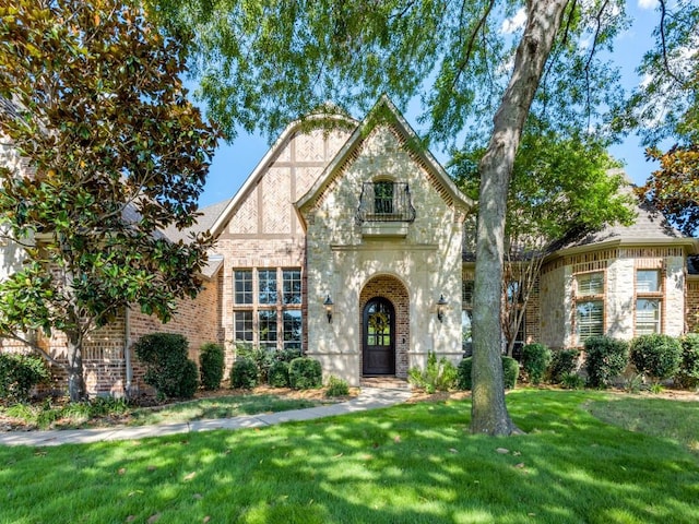 tudor house featuring brick siding and a front yard