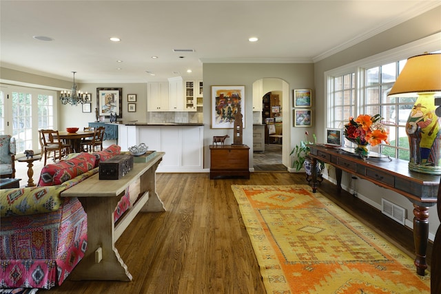 interior space with ornamental molding, arched walkways, plenty of natural light, and wood finished floors