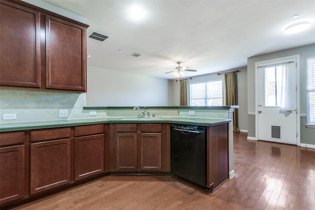 kitchen with a peninsula, a sink, visible vents, black dishwasher, and decorative backsplash