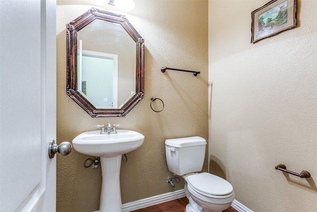 half bathroom with toilet, baseboards, and wood finished floors