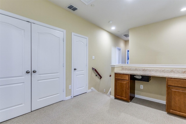 unfurnished office featuring recessed lighting, visible vents, built in desk, and light colored carpet