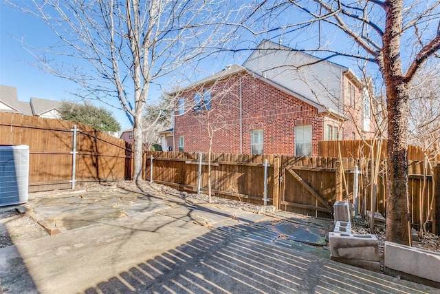 exterior space with central air condition unit, fence private yard, a gate, and brick siding