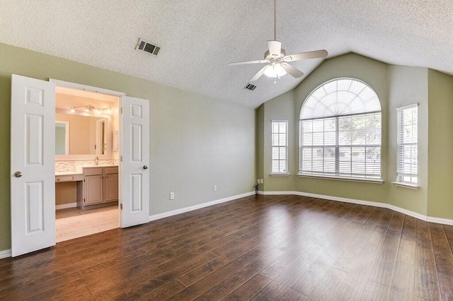 spare room with a ceiling fan, lofted ceiling, visible vents, and wood finished floors