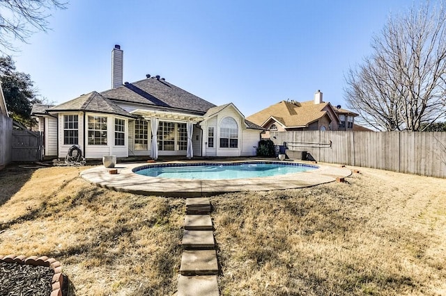 rear view of house featuring a chimney, a fenced backyard, and a fenced in pool