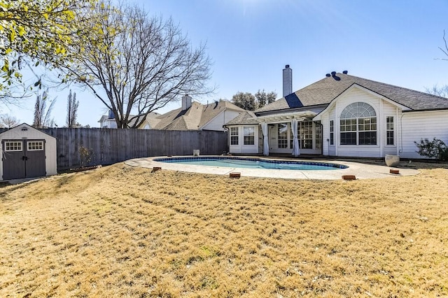 view of swimming pool featuring an outbuilding, a patio, fence, a fenced in pool, and a shed