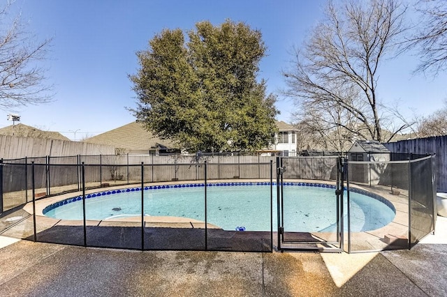 view of pool featuring a storage unit, an outdoor structure, a fenced backyard, and a fenced in pool