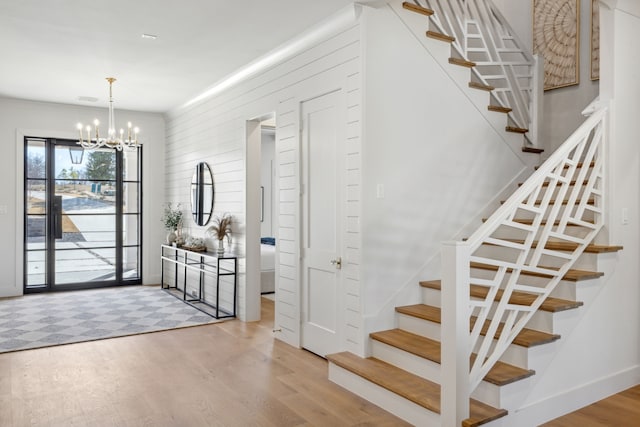 entrance foyer with a chandelier, visible vents, wood finished floors, and stairs